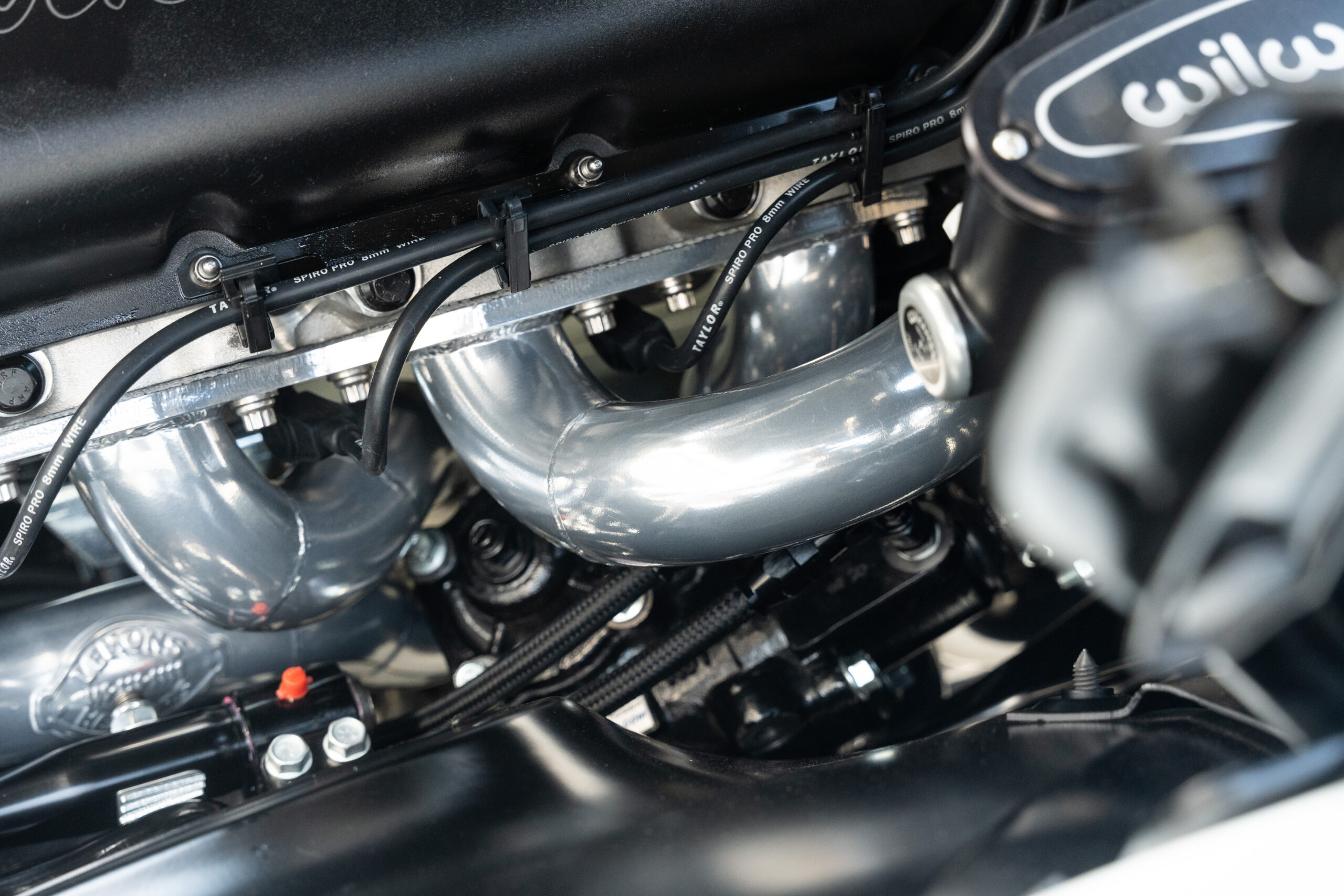 Close up of polished steel headers with smooth collector bends on a small block Chevy performance engine in Paso Robles, CA